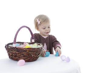 Little girl trying to open Easter eggs, isolated on white background