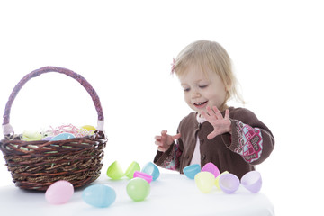 Little girl trying to open Easter eggs, isolated on white background