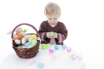 Little girl trying to open Easter eggs, isolated on white background