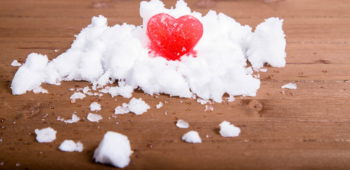 Bright red ice heart on a hill of white snow