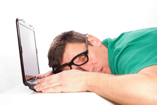 verzweifelter, m&uuml;der, schlafender Mann auf dem Laptop im gr&uuml;nen Shirt