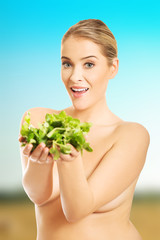 Portrait of happy nude woman giving lettuce