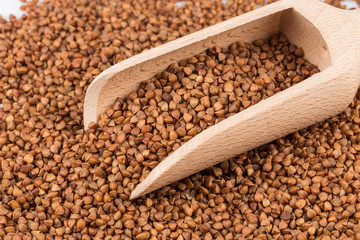 Uncooked buckwheat on wooden spoon