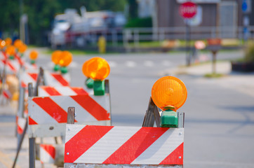 Row of red and white road traffic barricades with yellow lights