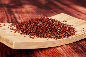 Red quinoa seeds on wooden table.