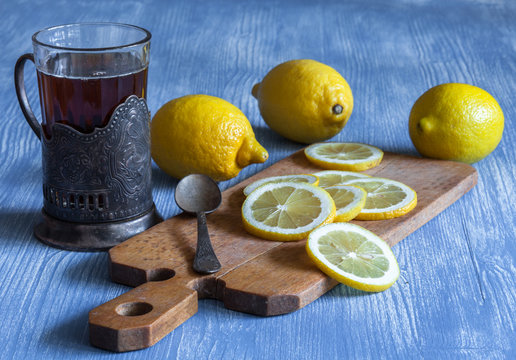 Ностальгия: стакан чая в металлическом подстаканнике и лимоны на деревянном столе.