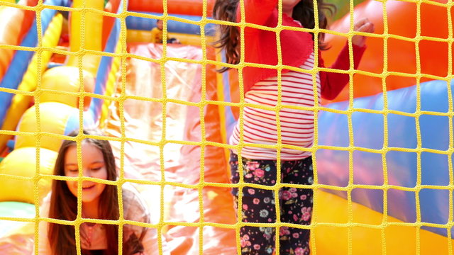 Two girls sliding on inflatable rubber castle playground