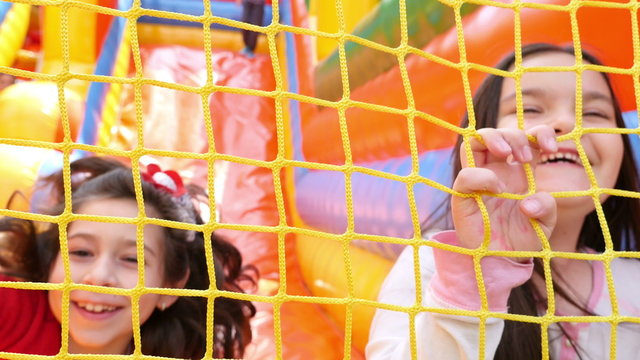 Two girls sliding on inflatable rubber castle playground