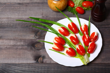 Appetizer in the form of tulips bouquet, tomatoes stuffed with cheese and green onions