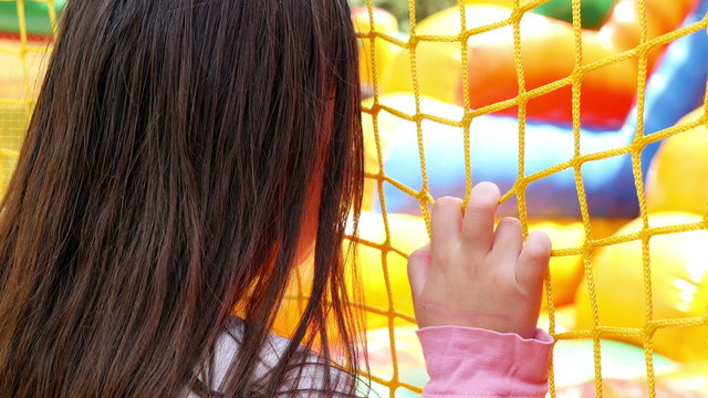 A girl is watching children playing on inflatable rubber castle playground