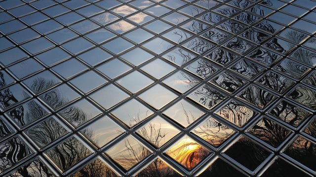 Fleeing mirror mosaic with distorted sunset behind the trees