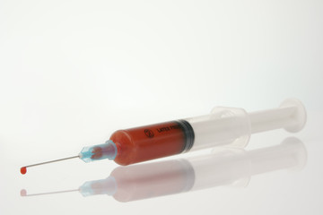 syringe with drop of blood, focus on drop