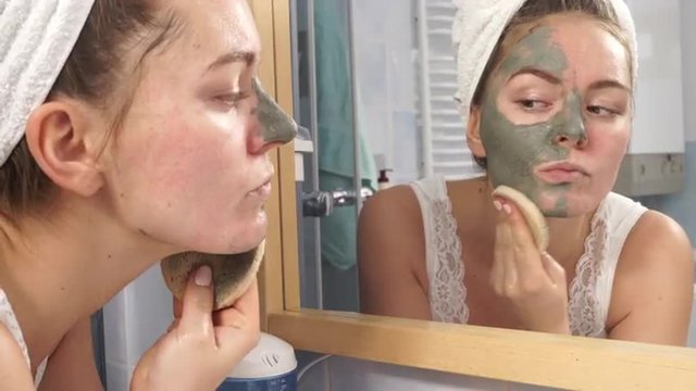 Woman removing facial clay mud mask in bathroom 4K