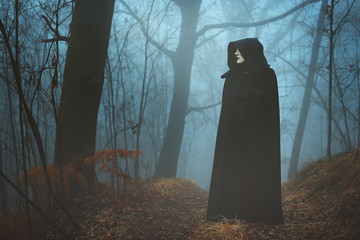 Black hooded person in the fog - obrazy, fototapety, plakaty