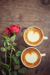 Fototapeta na wymiar Two cups of latte art coffee with red rose