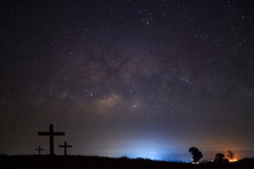 Silhouette of cross over milky way