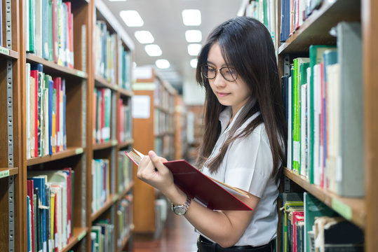 Asian student in uniform reading in the library at university