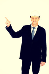 Smiling businessman with hard hat pointing up