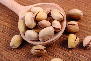 Pistachio nuts with spoon on wooden table, healthy eating