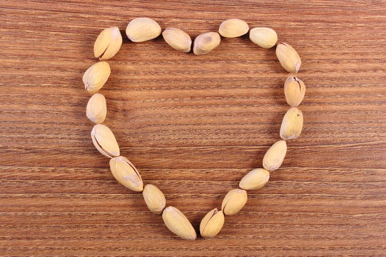 Heart of pistachio nuts on wooden table, healthy eating