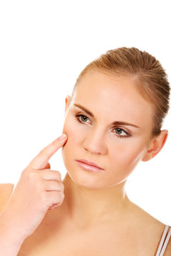 Unhappy young woman touching her pimple