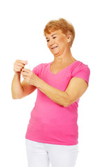 Obraz premium Smiling senior woman holding jar of pills