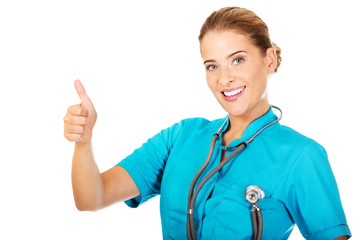 Young female doctor or nurse with stethocope shows thumb up