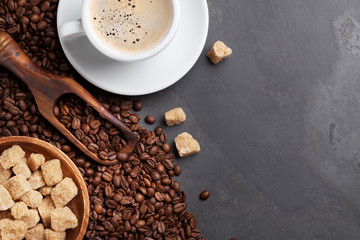Coffee cup, beans and brown sugar on stone table