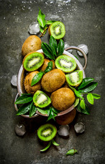 Fresh kiwi with leaves and ice in a pan.