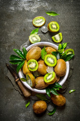 Cup fresh kiwi, leaves, and a knife.