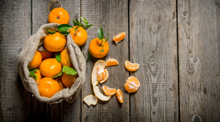 Fragrant tangerines in an old bag with a knife and peeled tangerines.