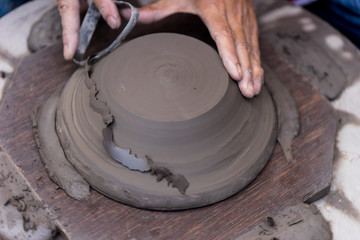 Hands working with clay on pottery wheel
