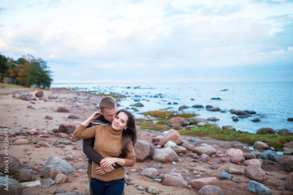 Wall mural Young couple hugging on a rocky seashore