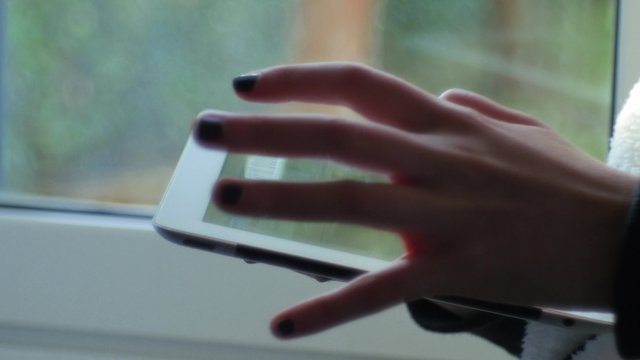 Girl near a window using a digital tablet
