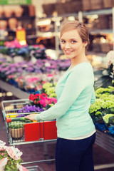 happy woman with shopping trollye buying flowers