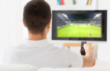 man watching football game on tv at home from back