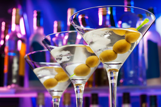 Olives in cocktail glasses and bar bottles 