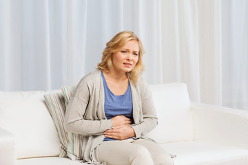 unhappy woman suffering from stomach ache at home