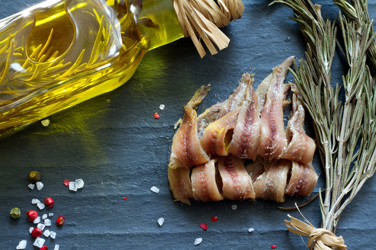 Anchovies with salt, oil and spices on black marble
