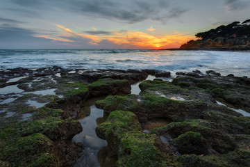 Magical sunset at sea in Portugal. Stones beautiful shape in the foreground.