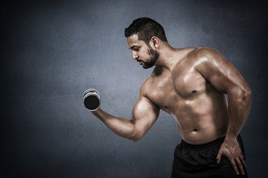 Muscular man lifting heavy dumbbell 