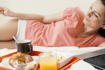 Fototapeta na wymiar Woman resting on bed and having breakfast.