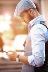 Young urban businessman professional on smartphone walking in street using app texting sms message on smartphone 