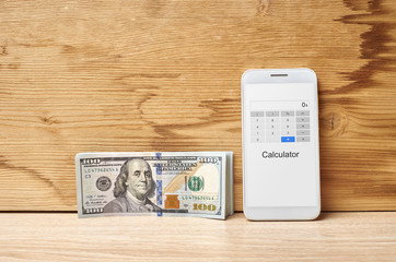 dollars and phone on a wooden table