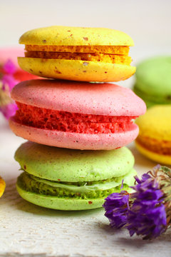 Tasty colorful macaroon on wooden table with dried flowers