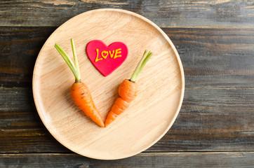 Obraz na płótnie Canvas Fresh carrots with love on wooden plate,Valentine day