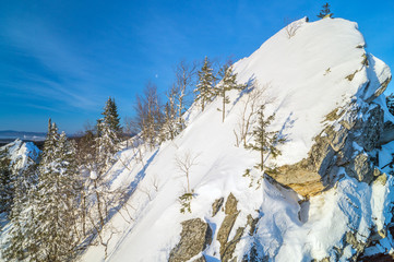 Вершина заснеженной скалы. Маленькие деревья.