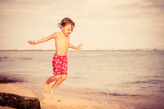 Portrait of little boy jumping on the beach at the day time