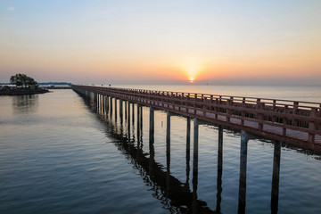 The wooden bridge in the sea with sunrise in the morning