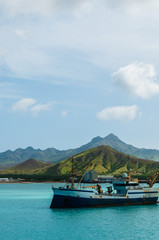 Old rusty Ship in the blue ocean at coast with cloud and green mountain background, Cape Verde island